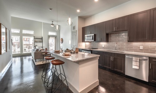 Model kitchen with island and counter seating in a 2 bedroom apartment at 301 Flower Mound in Flower Mound, TX.