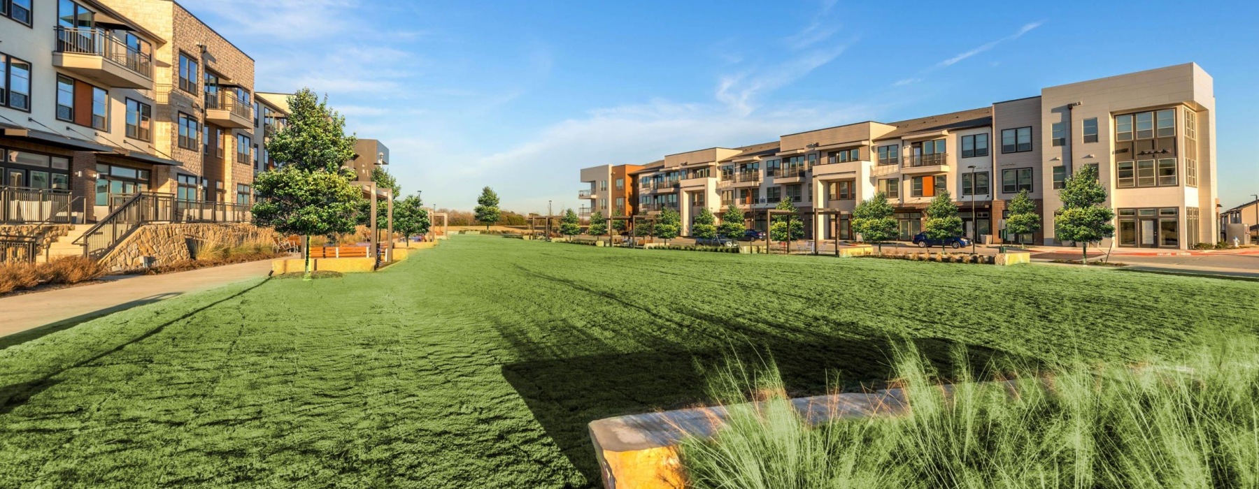 The grounds at our apartments in Flower Mound, TX, featuring a large grassy field and a view of the apartment complex.