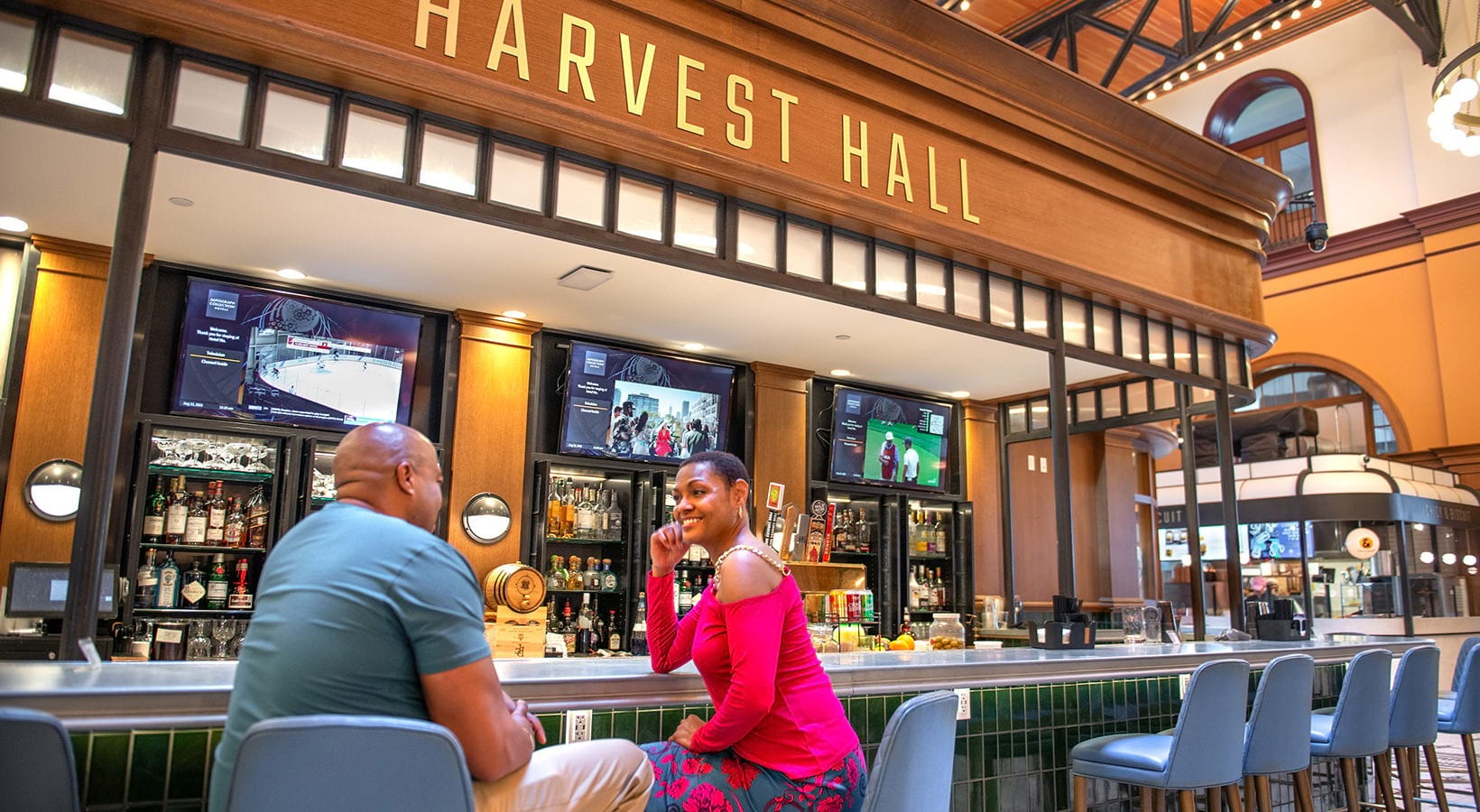 Harvest Hall A bar near our apartments in Flower Mound, featuring two people sitting on stools under a sign that reads