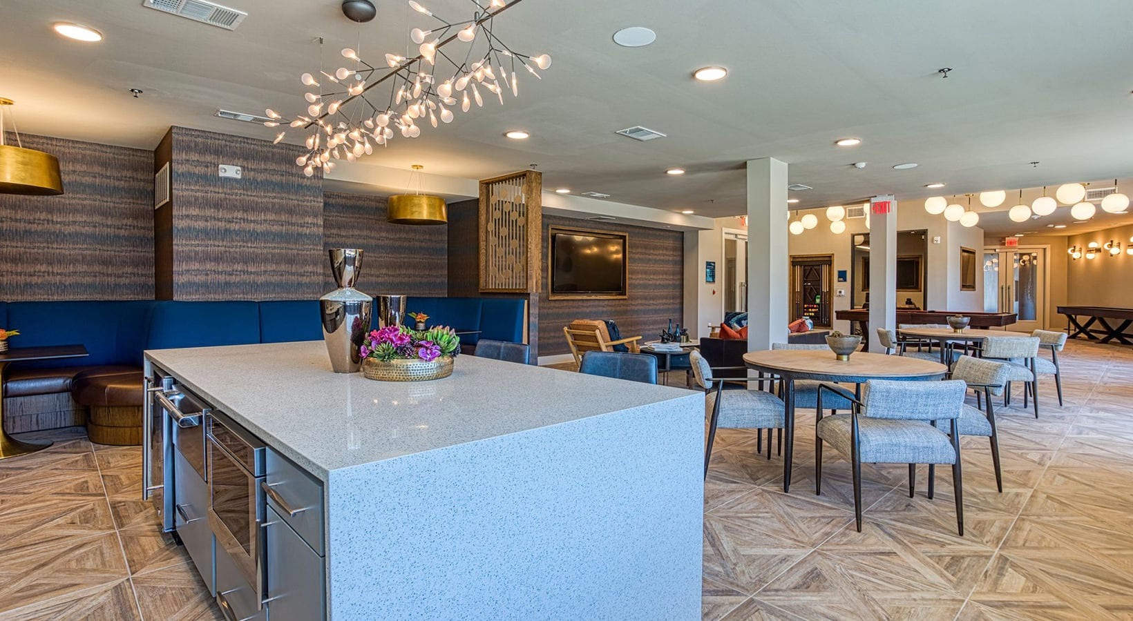 clubhouse Lounge and dining area at our apartments in Flower Mound, featuring wood grain floor panels and tables with chairs.